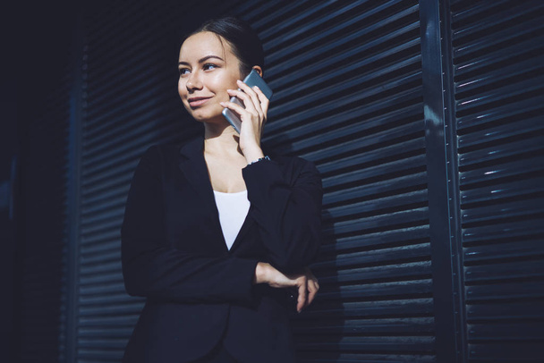 Happy business woman making positive international call via cellular phone during sunny day on urban setting, successful female entrepreneur enjoying good roaming connection on smartphone device - Foto, Imagen