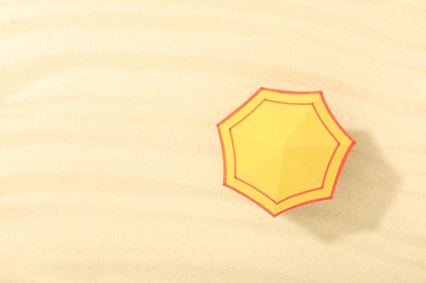 Κορυφαία θέα της παραλίας του χαρτιού με κίτρινη ομπρέλα σε υφή άμμου  - Φωτογραφία, εικόνα