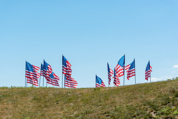 national flags of america on green grass against blue sky with clouds  - Zdjęcie, obraz