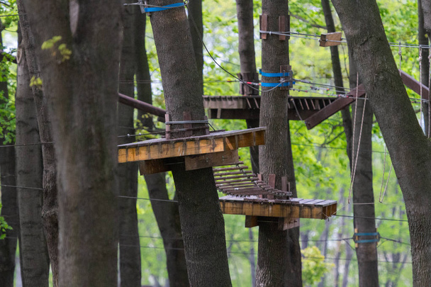 Rope park for team building. Obstacle course at height. Outdoor activities. Leisure in nature. Teamwork for the sake of victory. Corporate spirit. Games for friends. Wheels and boards as obstacles. - Photo, Image