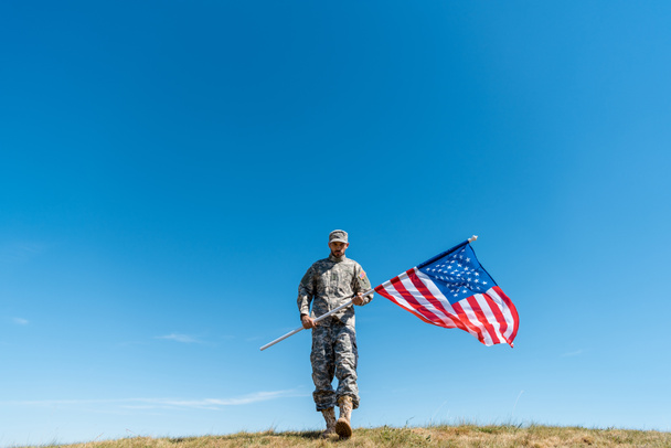 guapo soldado en uniforme caminando con bandera americana
  - Foto, Imagen