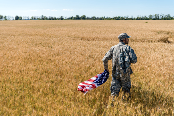 handsome man in military uniform holding american flag  - Foto, afbeelding