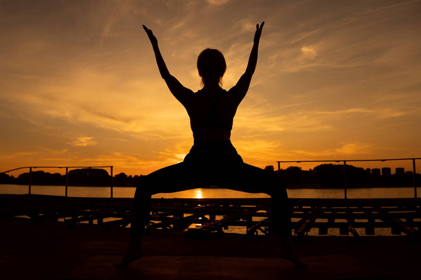 Nő gyakorló jóga naplementekor. Utkatasana, szék pózol - Fotó, kép