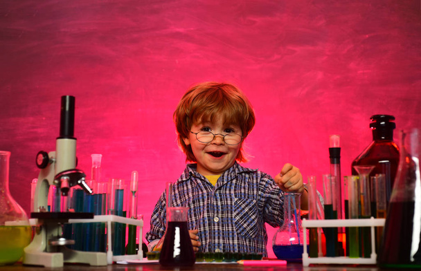 Kid from primary school. Lab microscope and testing tubes. First grade. Back to school and happy time Kid is learning in class on background of blackboard - Фото, изображение