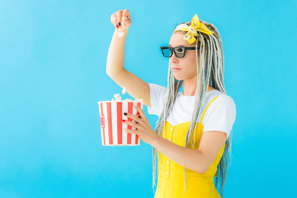 girl with dreadlocks in 3d glasses holding popcorn isolated on turquoise - Valokuva, kuva