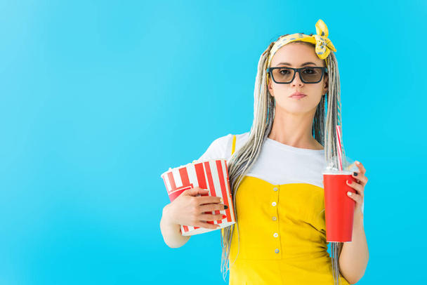 girl with dreadlocks in 3d glasses holding soda drink and popcorn isolated on turquoise - Photo, Image