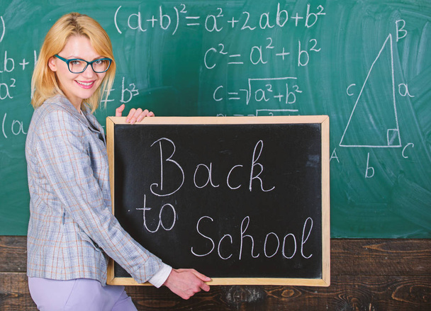 Great beginning of school year. Top ways to welcome students back to school. Teacher woman hold blackboard inscription back to school. It is school time again. School teacher happy welcome pupils - Photo, Image