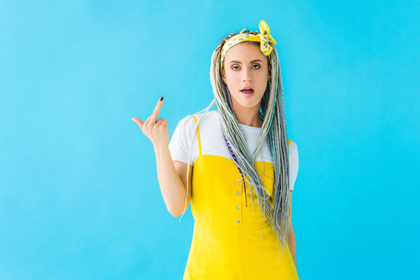 dissatisfied girl with dreadlocks showing middle finger isolated on turquoise - Foto, Bild