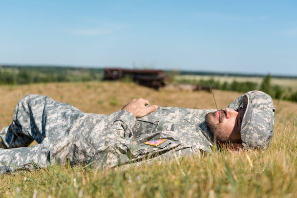 cheerful soldier in military uniform lying on grass  - Fotó, kép