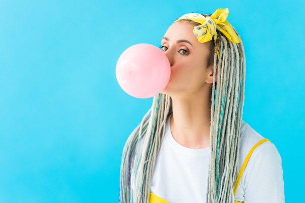 girl with dreadlocks and headband blowing bubblegum isolated on turquoise - Photo, Image