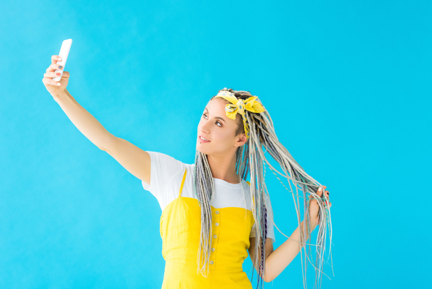 girl with dreadlocks taking selfie on smartphone isolated on turquoise - Photo, Image