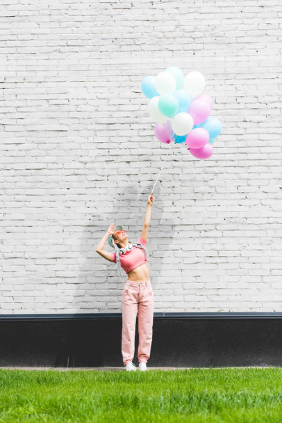 stylish girl posing with decorative balloons near brick wall - Photo, Image