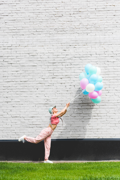 stylish girl posing with decorative balloons near brick wall - Foto, immagini