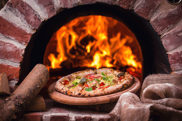 maukas pizza ulos uunista ravintolan keittiössä
 - Valokuva, kuva