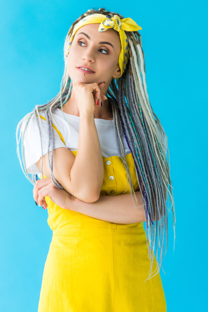 thoughtful girl with dreadlocks propping chin with hand isolated on turquoise - Fotografie, Obrázek