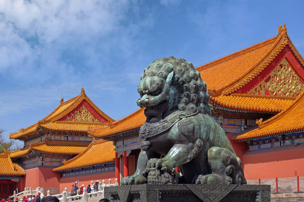 Marmurowy Pomnik Lwa wewnątrz Muzeum Pałacowego w Pekinie, przeciw czerwonym budynkom z pomarańczowymi dachami, z niebieskim letnim niebem w tle. - Zdjęcie, obraz