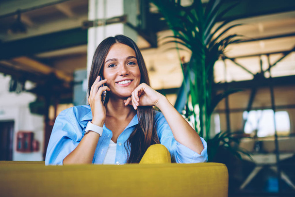 Smiling hipster girl casual dressed have smartphone conversation received happy news from work, positive caucasian woman making cellular call via application using wireless connection indoors - Φωτογραφία, εικόνα