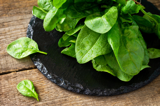 Fresh salad spinach leaves on the wooden kitchen table.  - Photo, Image