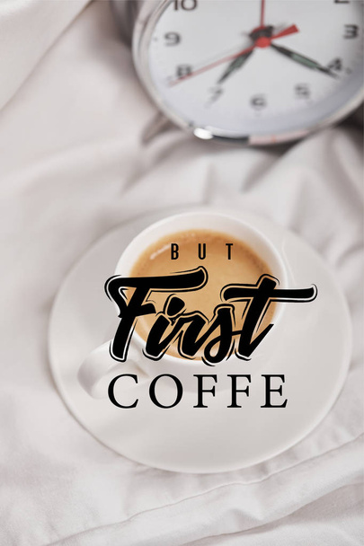 vue du haut du café en tasse blanche sur la soucoupe près d'un réveil en argent sur la literie avec mais première illustration de café
 - Photo, image