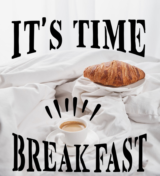fresh croissant on plate near coffee in white cup on saucer in bed with its time, breakfast lettering - Foto, Imagem
