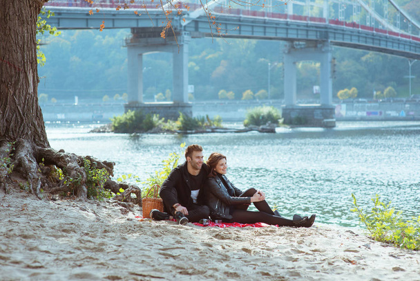 belo incrível engraçado alegre jovem casal (homem e mulher) abraçando ao ar livre pelo rio no fundo da ponte. Namorada e namorado. Conceito de família, piquenique, amor e amizade
 - Foto, Imagem