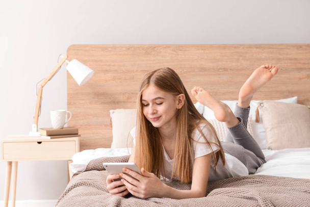 Linda chica adolescente con tableta en el dormitorio en casa
 - Foto, Imagen