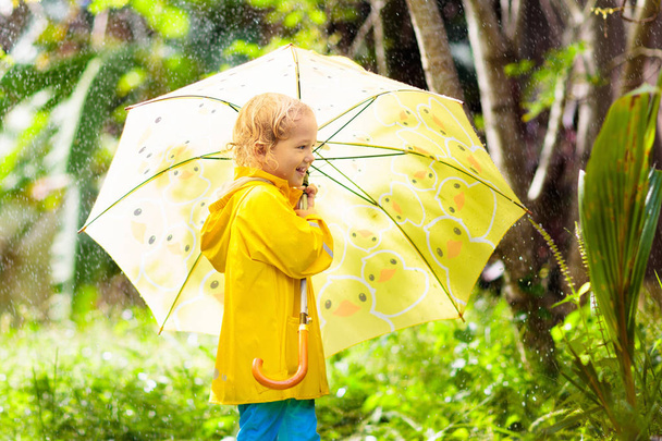 Child playing in the rain. Kid with umbrella. - Photo, Image