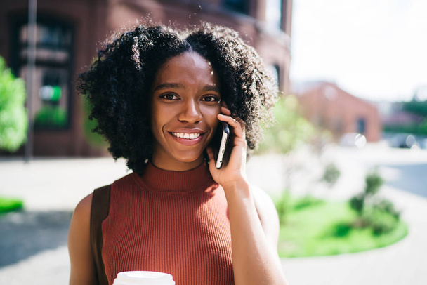 Close up portrait of happy female student connected to roaming calling to friend for talking on leisure, positive African American hipster girl using cellular phone for online communication - Foto, afbeelding
