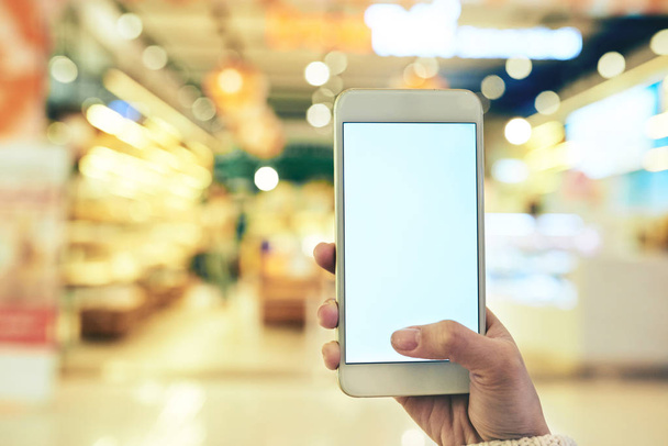 Mano de cliente femenina que utiliza la aplicación móvil cuando compra en el supermercado
 - Foto, Imagen