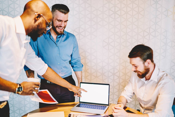 Позитивна група чоловіків-колег i сорочки розважаються під час робочого процесу в офісі. Успішні працівники насолоджуються співпрацею в дружній атмосфері. Успішна зустріч мозкового штурму
  - Фото, зображення