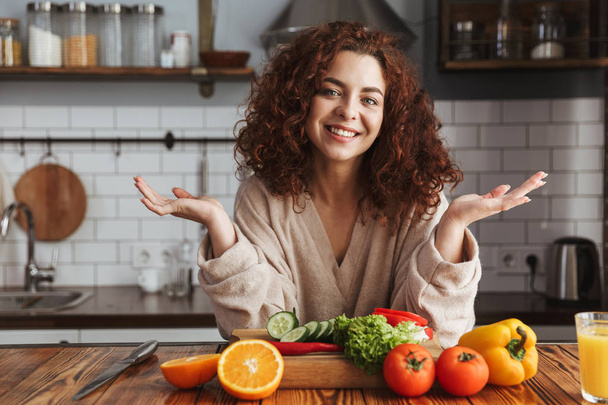 Photo of pretty caucasian woman smiling while cooking salad with - Foto, Imagem