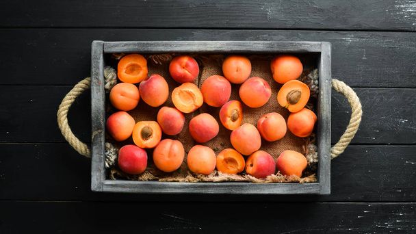 Fresh apricots with green leaves in a box. Rustic style. Top view. Free space for your text. - Foto, Imagen