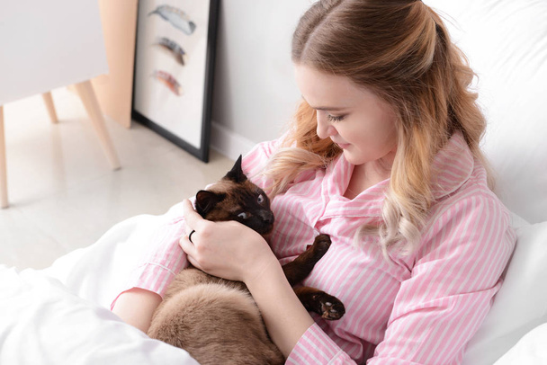 Young woman with cute Thai cat in bedroom - Фото, изображение