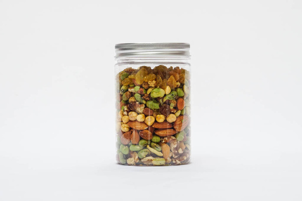 Variety of nuts and beans in plastic jar on isolated white background - 写真・画像