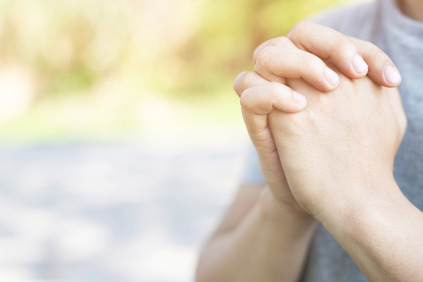 Молитвенные руки верного зрелого молодого человека сложены в молитве на открытом воздухе утром. молитва о святой концепции веры, духовности и религии
. - Фото, изображение