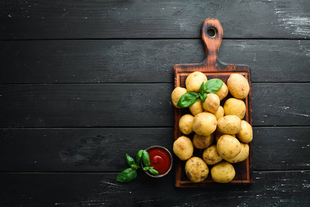 Fresh potatoes on a black background. Organic food. Top view. Free space for text. - Фото, зображення