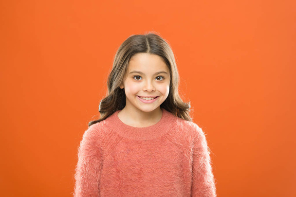 Happy childhood. Child care and psychology. Wellbeing and health. Radiating happiness. Smiling child close up. Facial care. Cosmetology beauty concept. Girl child cute face orange background - Photo, Image