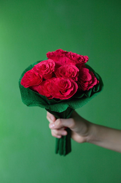 Een boeket rozen in de hand, met de handgemaakt van papier. - Foto, afbeelding