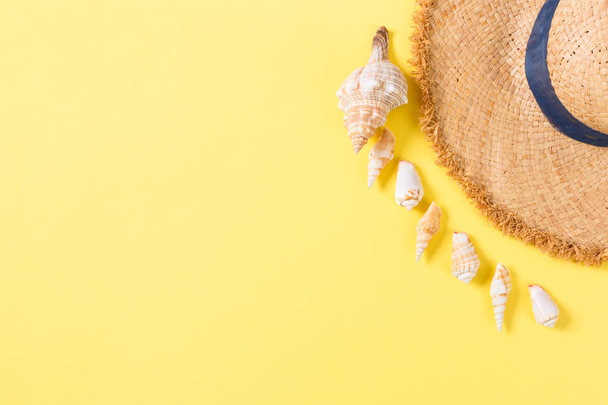 Fondo de vacaciones de verano con sombrero de paja y conchas marinas sobre fondo amarillo vista superior con espacio de copia
 - Foto, imagen