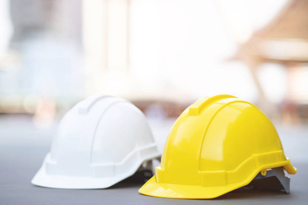 žlutá a bílá tvrdá bezpečnost Noste helmu v projektu v budově staveniště na betonových podlažbách ve městě se slunečním zářením. přilbu pro zaměstnance jako inženýra nebo pracovníka. koncepce bezpečnost nejprve. - Fotografie, Obrázek