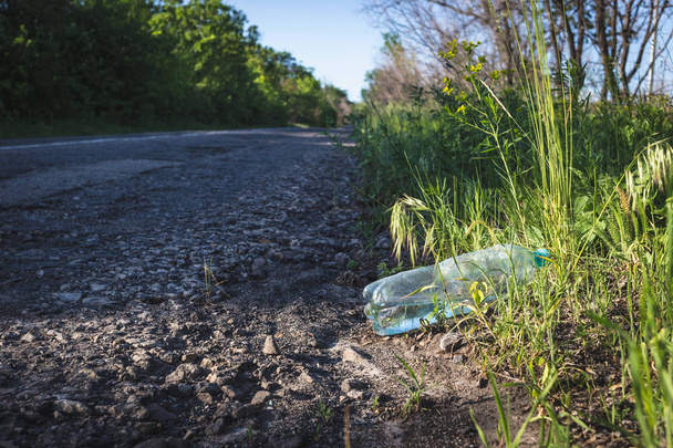 Пластикова пляшка з водою біля дороги
.  - Фото, зображення