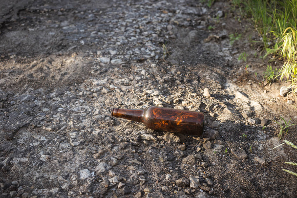 Brązowa butelka piwa przy drodze. - Zdjęcie, obraz