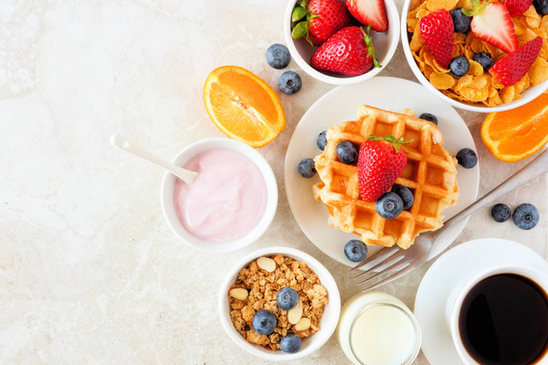 Scena della tavola da colazione. Frutta, cereali, waffle, yogurt e caffè. Vista dall'alto su uno sfondo di pietra brillante
. - Foto, immagini