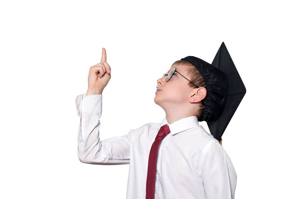 Chlapec ve čtvercové čepici a brýle ukazuje prstem nahoru. Školní koncept. Izolovat - Fotografie, Obrázek