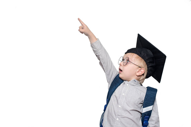 Überraschter Schüler im Anzug, Brille und Akademikerhut zeigt mit dem Finger nach oben. Schulkonzept. isolieren - Foto, Bild