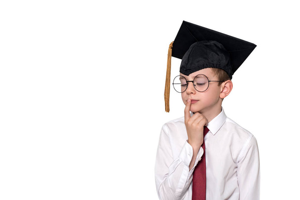 Porträt eines nachdenklichen Jungen in weißem Hemd, Brille und akademischer Mütze. Schulkonzept. isolieren - Foto, Bild
