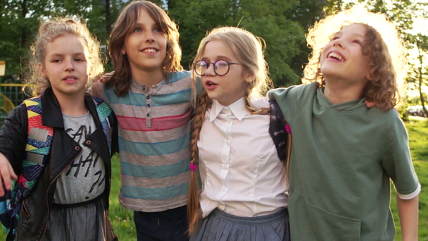 Close portrait of happy schoolchildren on the background of the setting sun. Four classmates. Back to school - Footage, Video