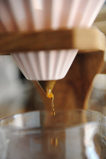 Bliska kapanie kawy. Alternatywne browarnictwo w różowej ceramicznej kroplownik na drewnianej podstawki. - Zdjęcie, obraz