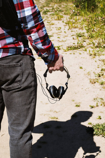 Хіпстер вишуканий чоловік у плетеній сорочці тримається за руку і ходить з ретро старовинними старовинними 80-х років, 90-х років стиль портативні навушники радіо звукова касета магнітофон бумбокс з аудіо стрічкою касета всередині
  - Фото, зображення