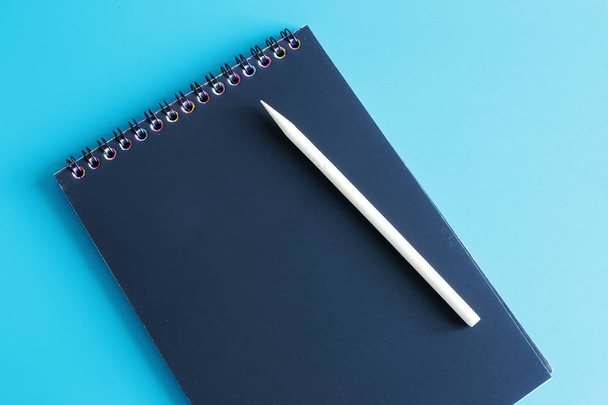 Notepad with black sheets and a wooden scraper are on a bright smooth background, a place for writing letters, write text on black paper - Photo, Image